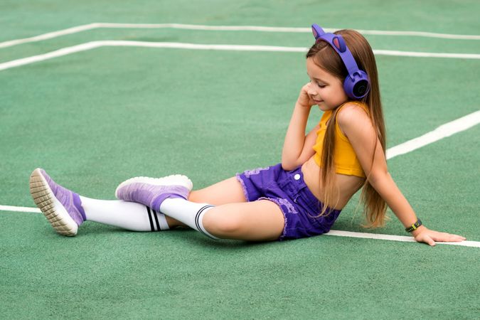 Female child sitting on sports ground