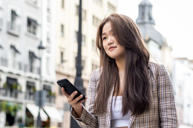 Young Asian Woman Walking and Using Smartphone in the City