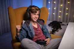 Cheerful boy in headphones playing videogame