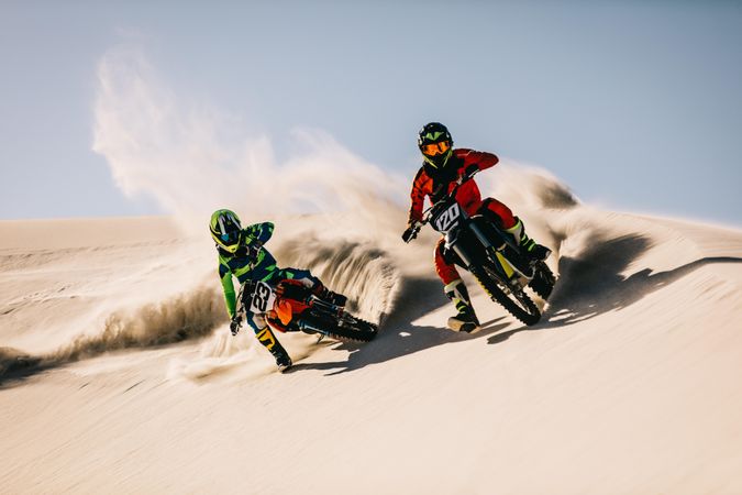Two motocross riders speeding over the sand dunes