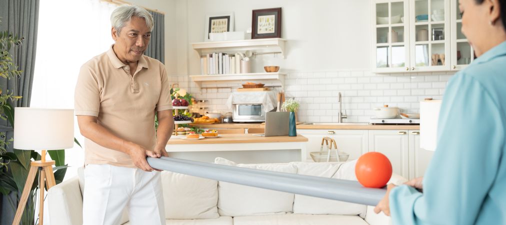 Asian older couple playing rolling ball for practice balance and concentrate in the living room