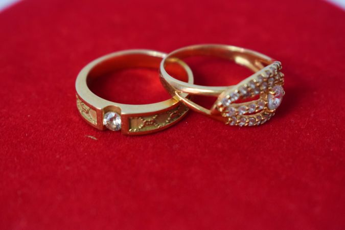 Two diamond gold wedding bands on red material with copy space