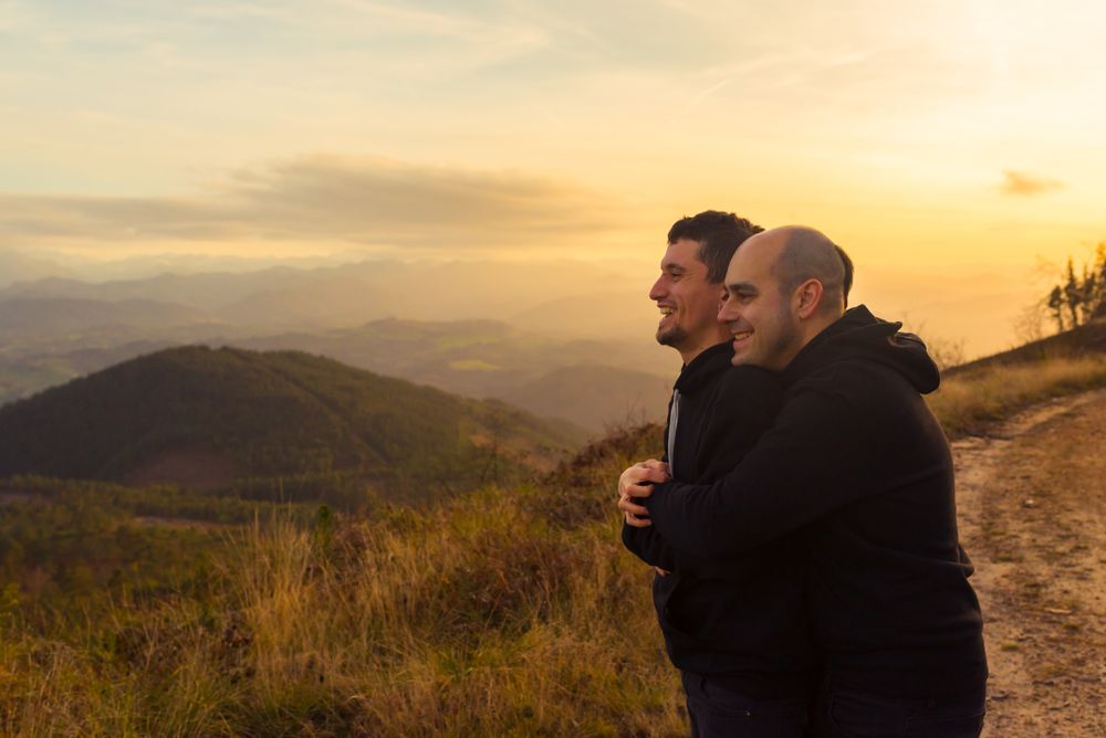 Men hugging on road on hill