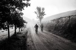 Back view of two people riding bicycle on dirt road in grayscale bDwXk4