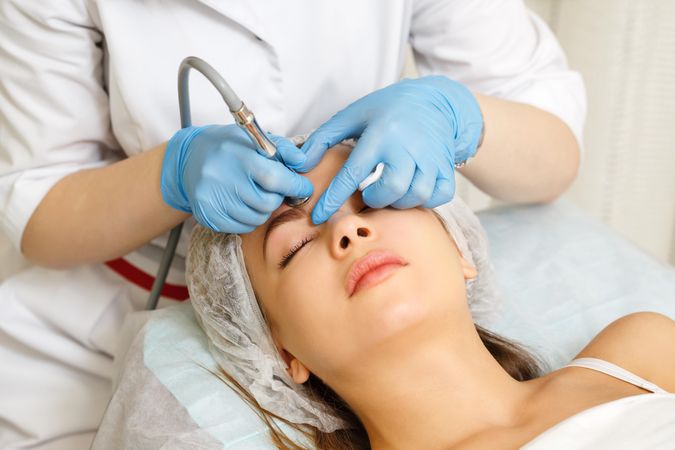 Woman having facial beauty treatment with instrument above her eyebrows