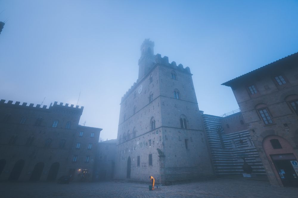 Aged stone buildings on square in mist