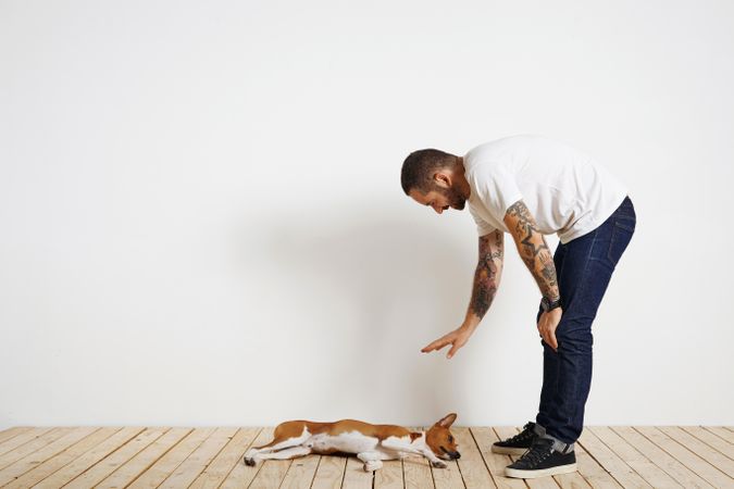 Casual, tattooed man teaching dog commands