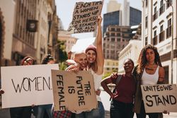 Crowd of protesters hold signs and rally on road