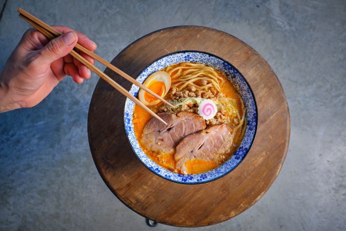Anonymous person eating appetizing Asian noodle soup with chopsticks