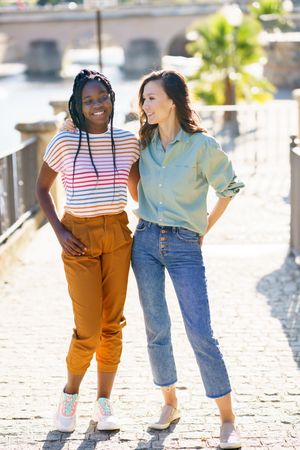 Female friends in casual clothing standing on cobble stone path