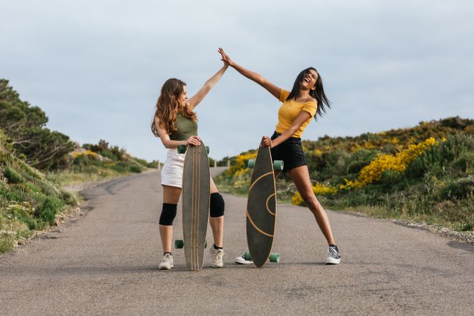 Cheerful diverse women giving high five on road