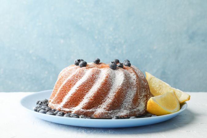 Cake with powder sugar and blueberry on blue background, space for text