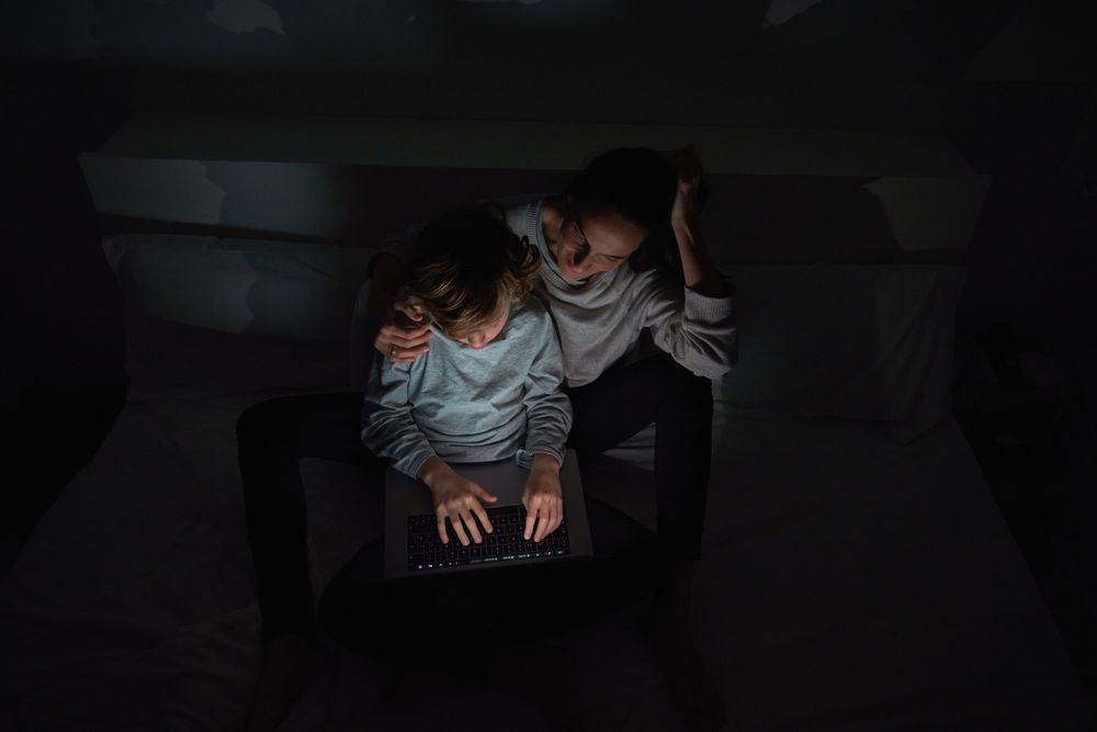 Mother helping son to do homework in darkness