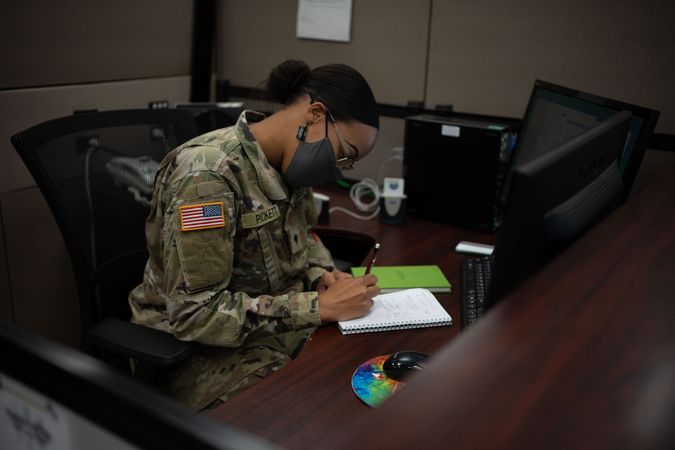 US female soldier with facemask working on desk