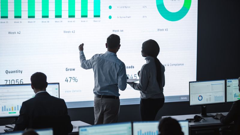 Business Team Analyzes Data on Large Screen.