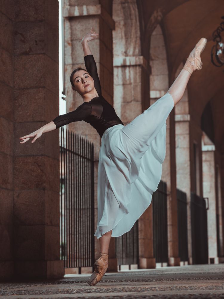 Flexible woman ballerina dancing in pointe shoes in arched passa