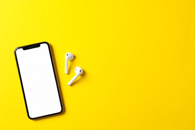 Phone with empty screen on yellow background, top view