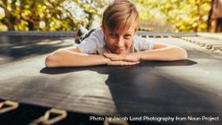 Small boy lying on trampoline outdoors 0vOmR5