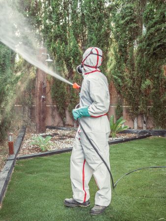Fumigator in uniform spraying substance on garden