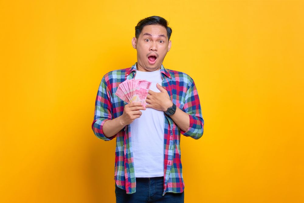 Asian man surprised to win money in studio shoot