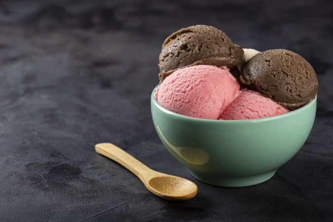 Bowl with Neapolitan ice cream on dark background.