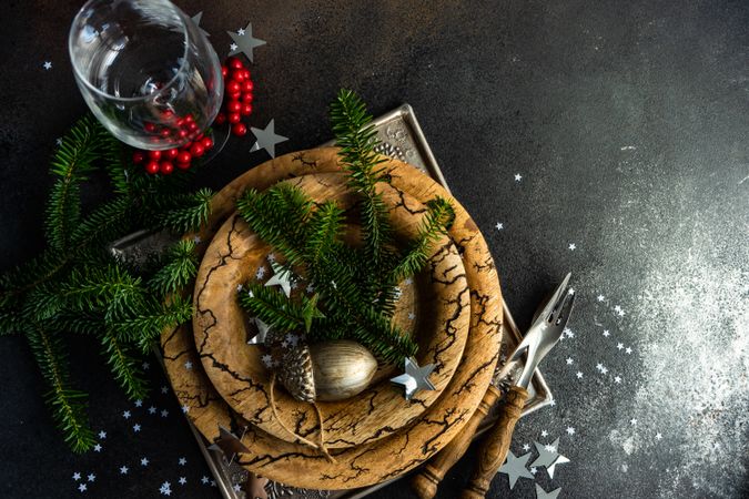 Rustic plates, cutlery and glass with wintry pine and ornament