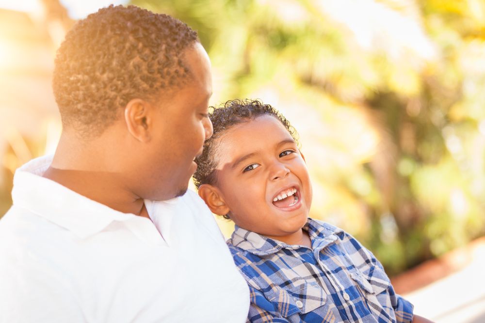 Black Son Talking With Father Outdoors