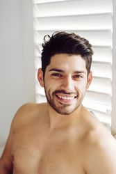 Young cheerful naked man leaning on window