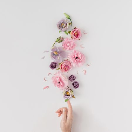 Hand with pink and violet flowers on light background