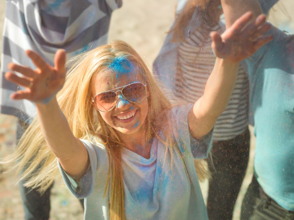 High Angle Shot of a Blonde Woman Throwing Colorful Powder in the Crowd Amidst Hindu Holi Festival
