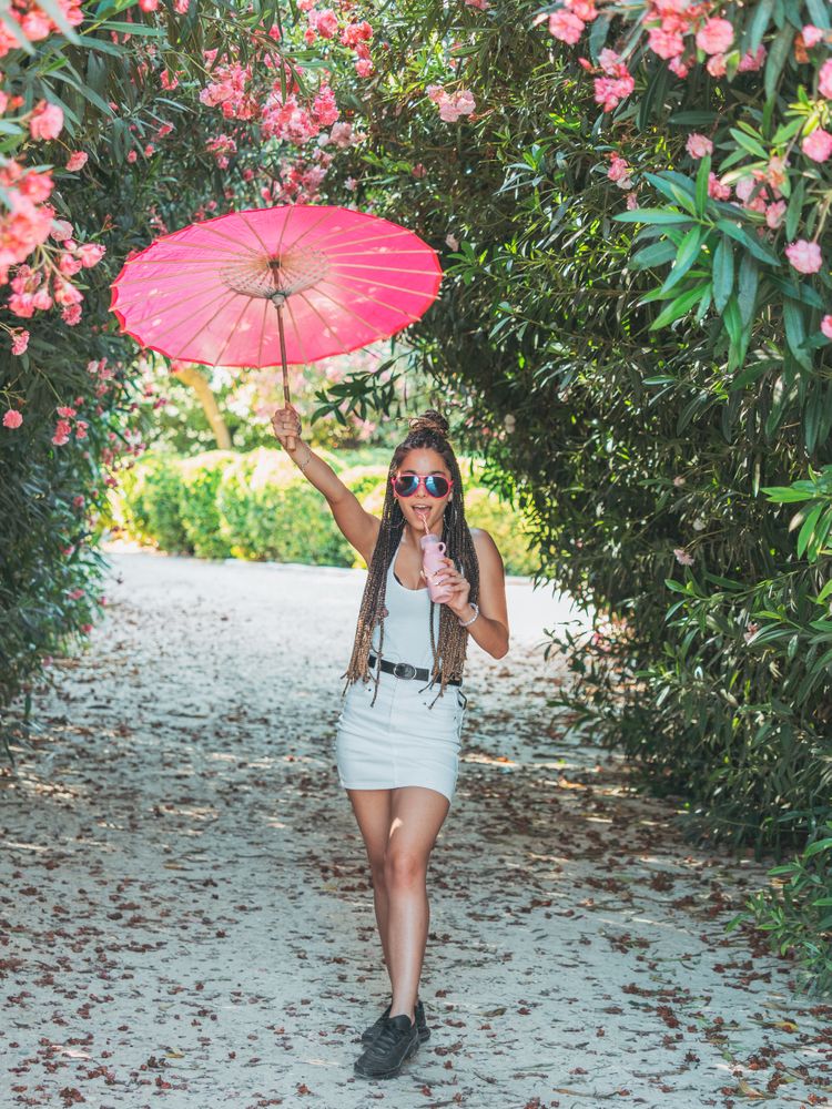 Female with umbrella standing near blooming trees