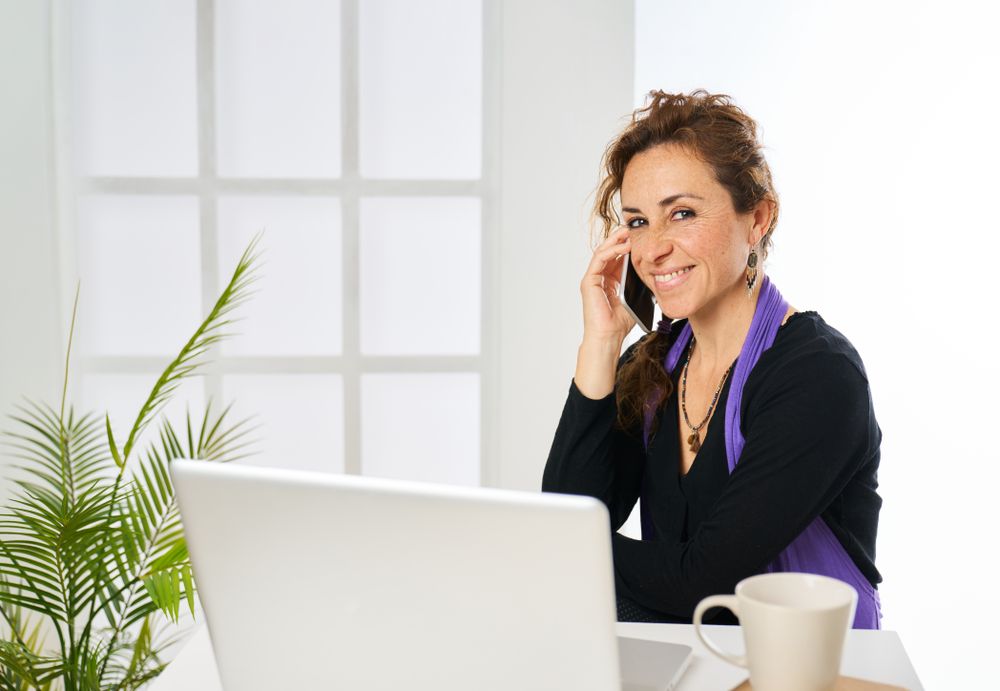 a woman working at the computer and talking on the phone