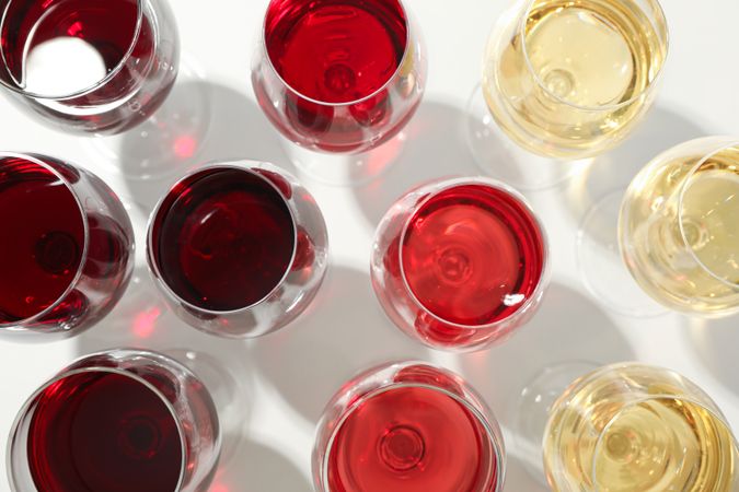 Glasses with different wine on plain background, closeup and top view