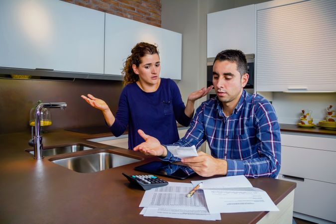 Couple arguing over their bills together in the kitchen