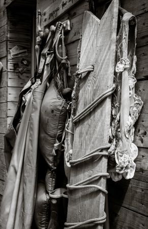 Close up of fishing clothes and board resting on wooden building, monochrome