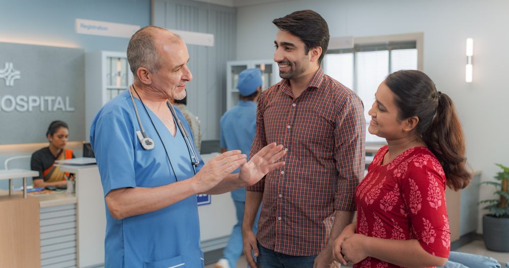 Indian Couple Visiting a Local City Hospital for a Health Check Up: Young Husband and Wife Talking to Their Doctor