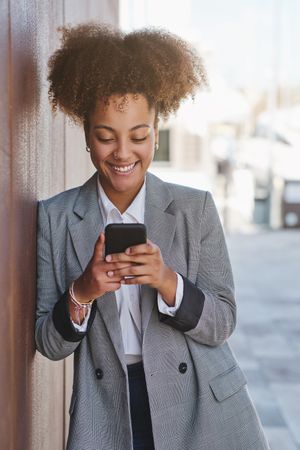 Carefree Black woman browsing smartphone on street