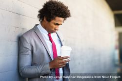 Man standing outside with his head down holding a coffee cup bYBL10