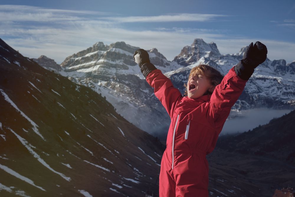 Child shouting against snowy mountain range