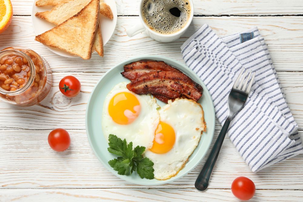 Full breakfast with eggs, beans, bacon, tomatoes and coffee