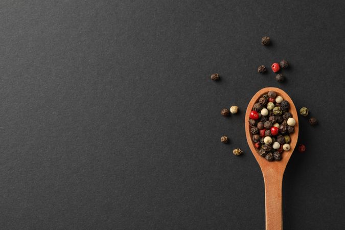 Looking down at wooden spoon of colorful peppercorns, copy space