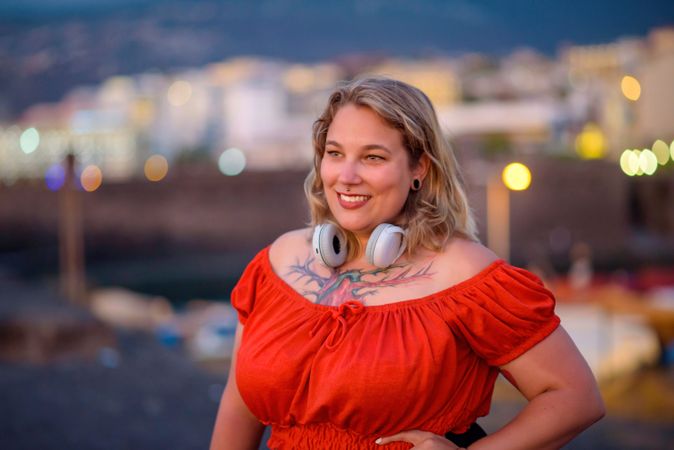 Smiling woman with tattoo and headphones on street