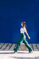 Young happy trendy woman walking in city against blue door