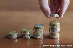 Person stacking coins on increasingly larger stacks 5zPLPb