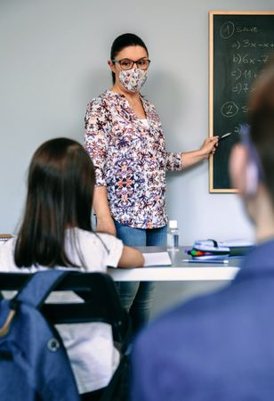Teacher with mask explaining exercises in math class