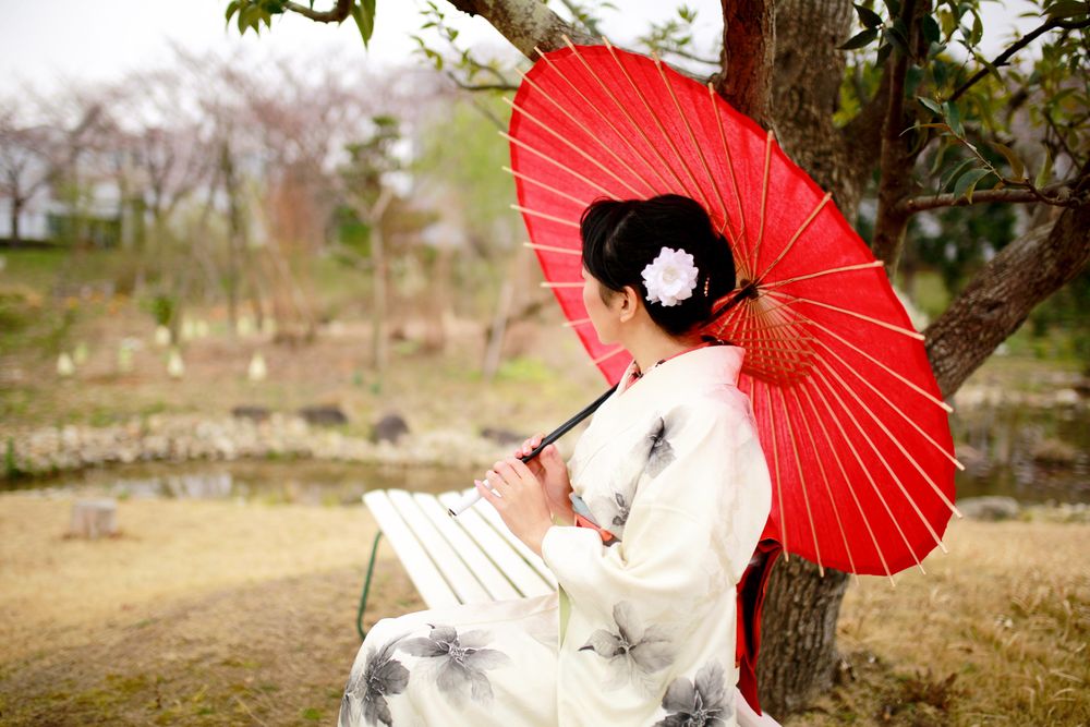 Woman in light and red floral kimono holding red umbrella