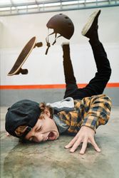 Boy falling from skateboard on concrete ground