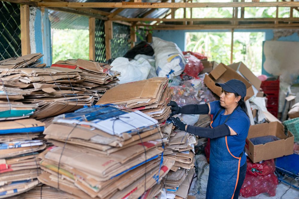 Hispanic Woman Managing Recycled Cardboard Inventory in Warehouse