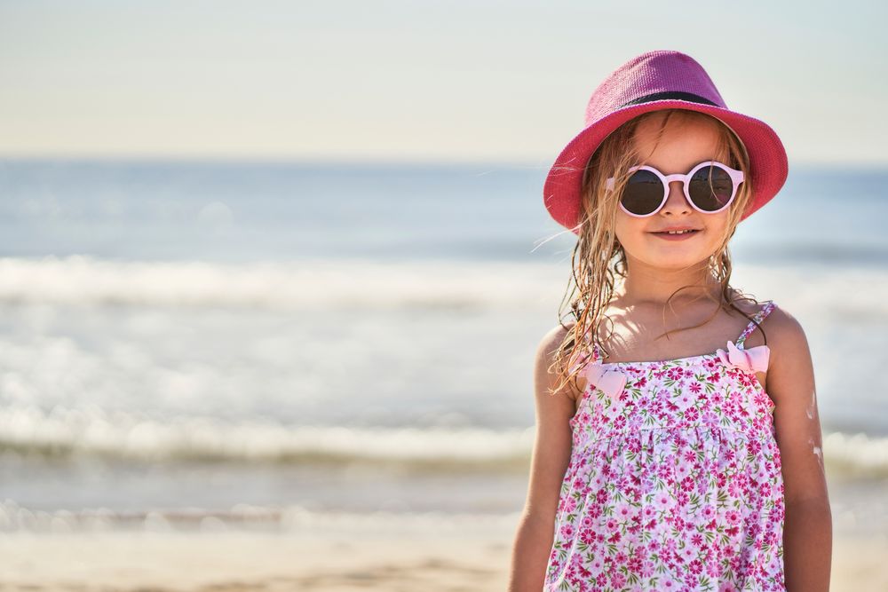 portrait of a girl with cap and sunglasses at the beach