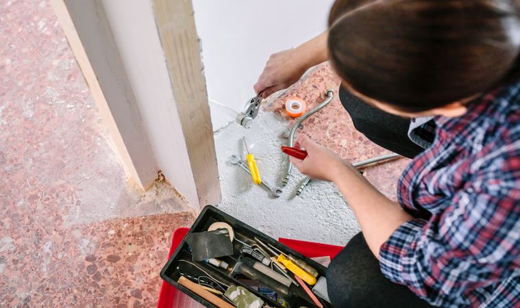 Female plumber doing heating installation on a construction site